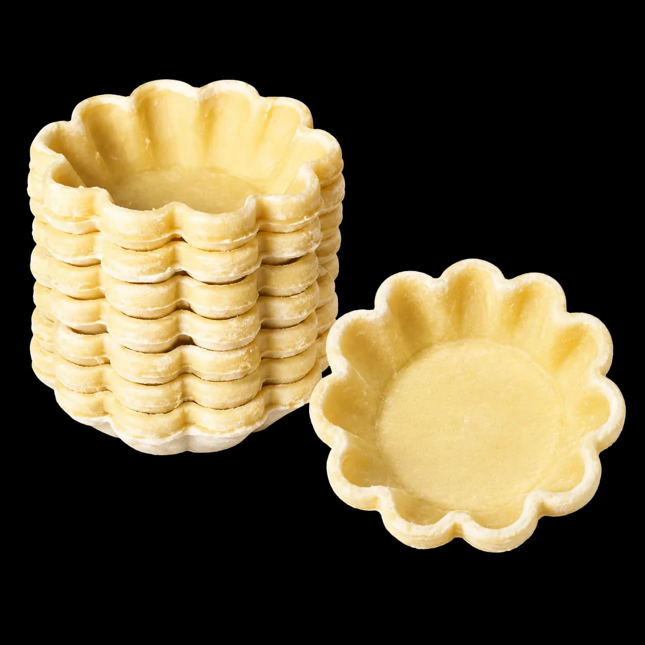 Stack of unbaked fluted egg tart shells beside a single shell